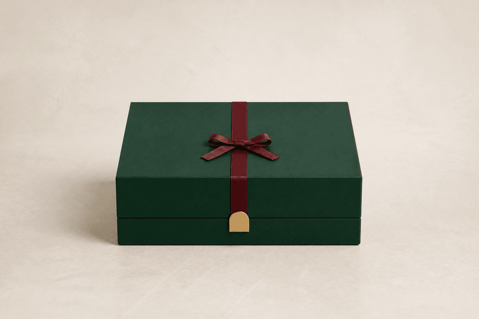 Photographie d’un coffret cadeau vert forêt centré, noué d’un ruban bordeaux